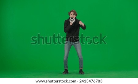 Male activist with raised fist shouting menacingly into megaphone in studio on green screen. Front view of a pro protest man. Protest action, fight for human rights, strike.