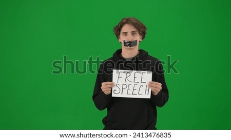 A man with his mouth taped with black tape holds a poster with the inscription Free speech. A Protestant man in the studio on the green screen close up. Conceptualizing the idea of free speech.