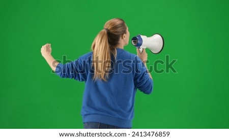 Woman facing away from camera speaking into megaphone with raised fist. Back view of a woman with a mouthpiece on a green screen close up. Protest action, fight for women's rights, strike.