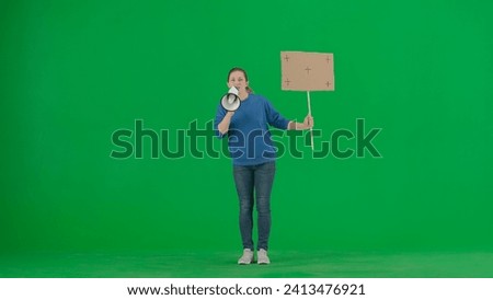 Woman speaking into a megaphone and holds a blank placard in her hand. A woman with a mouthpiece and placard on a green screen. Protest action, fight for women's rights, strike.