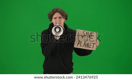 A man speaks into a megaphone and holds a placard that reads Save Our Planet. Man with a mouthpiece and a poster on a green screen close up. Save planet, climate changes concept, ecology.