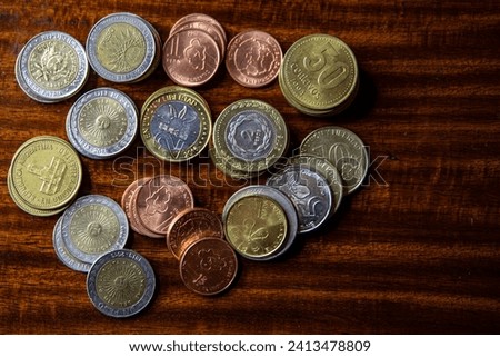 Argentine coins of different values on a wooden background. In disuse due to uncontrolled monetary emission. Inflation. Royalty-Free Stock Photo #2413478809