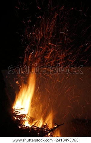 Fire blazing, sparks flying through the night sky, low shutter speed, motion blur, bright flame, colorful, depth of field. 