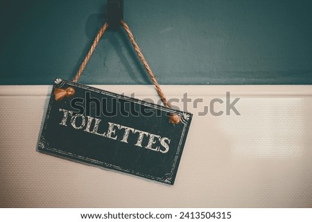 toilete sign hanging on the green white wall