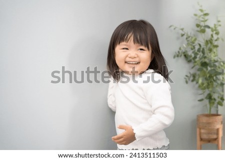 A 2 year old toddler smiling and playing in the living room.