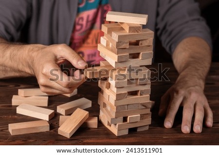 Hand of engineer playing a blocks wood tower game on blueprint or architectural project. Royalty-Free Stock Photo #2413511901