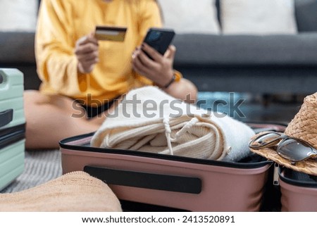 A travel bag ready for a trip, and a background image of a woman paying for accommodation with a credit card