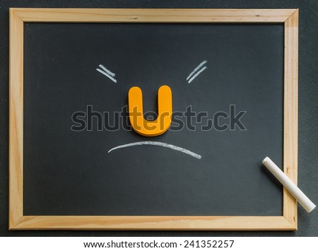 Wooden U character on black board