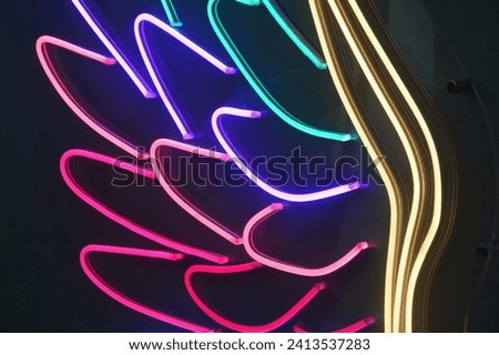 Neon glowing curved lines on a black background. Colorful stripes, bright colored elements. Abstract background.