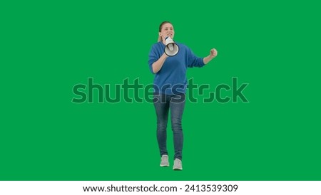 Female activist with raised fist shouting into megaphone in studio on green screen. Protest action, fight for women's rights, strike. Advertising, promo, chroma key.