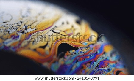 Paint blend. Holographic sphere. Defocused blue orange color stain bubble oil fluid ink mix wave motion marble texture on dark black abstract art background.