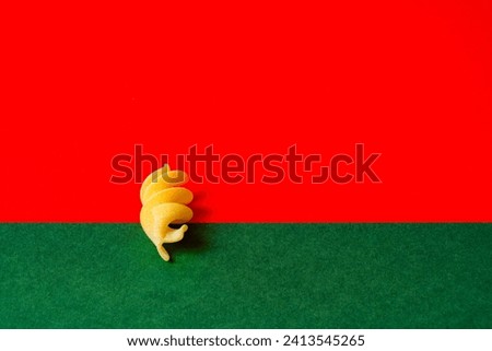 Alone fusilli pasta against a bold red and green background, italian pasta concept Royalty-Free Stock Photo #2413545265
