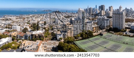 Panoramic view of aerial Lombard Street, an east–west street in San Francisco, California. Famous for steep, one-block section with eight hairpin turns. Tennis courts in San Francisco. Royalty-Free Stock Photo #2413547703
