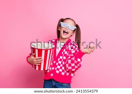 Photo of cute cheerful girl wear trendy clothes eat tasty pop corn watching cartoon film empty space isolated on pink color background