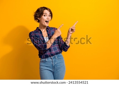 Portrait of impressed ecstatic girl with short hair wear checkered shirt directing at sale empty space isolated on yellow color background