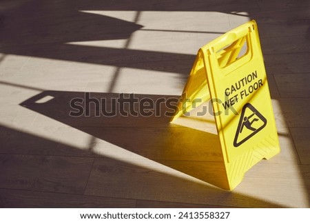 Yellow warning sign on the floor alerts to potential hazards, cautioning about a wet surface. An essential safety measure during maintenance, this sign emphasizes the need for care to prevent slips. Royalty-Free Stock Photo #2413558327