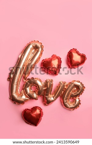Pale pink Foil Balloons in the shape of the word Love with hearts on pink background. Love concept. Holiday, celebration. Valentine's Day party decoration.