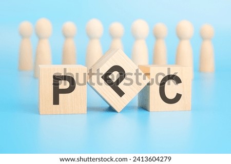 forming a conceptual word with blocks in the foreground - PPC (Pay Per Click). the blocks are located on a blue surface in front of wooden figures symbolizing people.