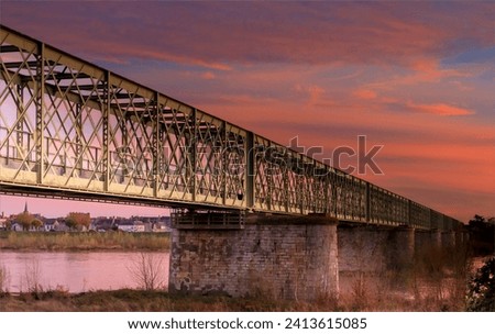 Metal bridge crossing the Loire river against a beatiful sunset of a blue and pink sky