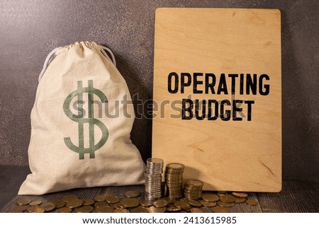 Closeup on businessman holding a card with text OPERATING BUDGET, business concept image with soft focus background and vintage tone