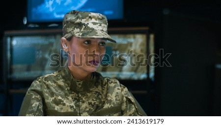 Close up of Caucasian pretty woman wearing camouflage clothes sitting at laptop computer and working in monitoring room in army. Female soldier in military data center. Beauiful lady works in troop. Royalty-Free Stock Photo #2413619179