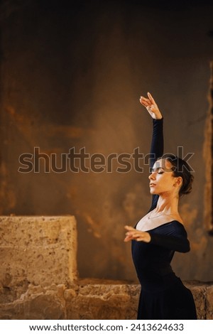 Gracious ballerina dedicated to ballet is performing her art and dancing with her elegant movements at abandoned place. Metaphor of fragile ballerina soul struggling with chaotic world around her. Royalty-Free Stock Photo #2413624633