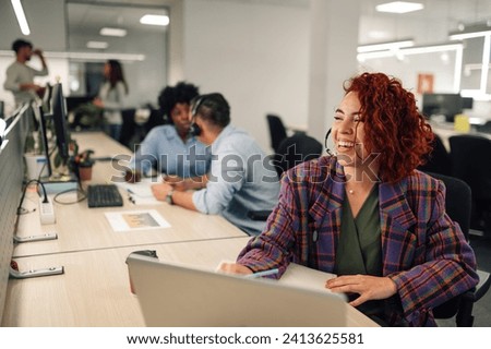 Smiling hispanic customer services agent woman with headset working in an office. Portrait of a a latino female agent working on a laptop in a call center and talking with clients and customers. Royalty-Free Stock Photo #2413625581