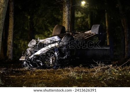 Wrecked car upside down after accident at night in the trees Royalty-Free Stock Photo #2413626391