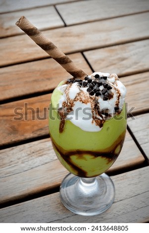 a glass of avocado float served with chocolate chips