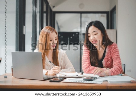 Happy multiethnic smiling business women working together in office, using calculator and laptop computer to calculate financial report.