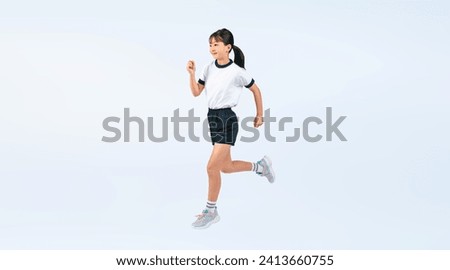 A full-body photo of an elementary school girl jumping wearing gym clothes.