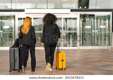 Confidence Businesswoman partnership dragging suitcase walking to airline check in counter in airport terminal. Business people work and travel, holiday vacation and public transportation concept. Royalty-Free Stock Photo #2413678211
