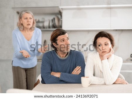 Outraged elderly female pensioner scolds her son and daughter-in-law for infantile behavior, unworthy behavior Royalty-Free Stock Photo #2413692071