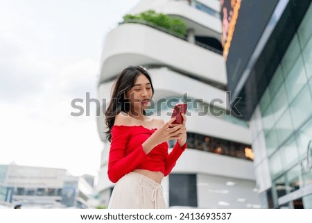 Asian woman using phone in a central business district area with a beautiful smile