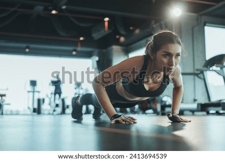 Sporty woman performing push-ups from the floor in the gym. Royalty-Free Stock Photo #2413694539