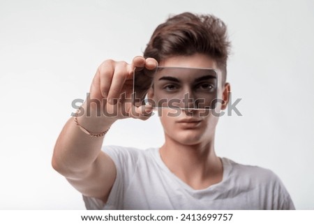 Man's eyes are intriguingly magnified by glass, creating a unique visual juxtaposition against a light backdrop