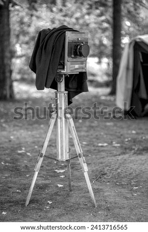 An old antique camera stands in the forest ready for shooting.