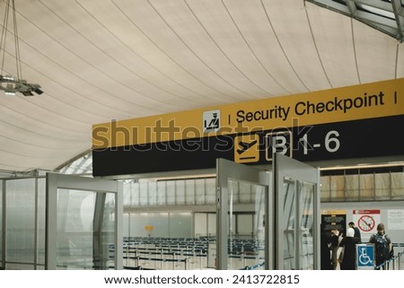 security check sign hanging from airport terminal ceiling