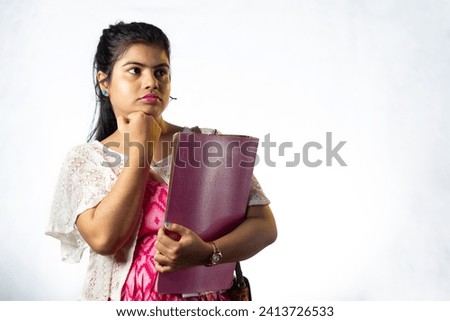 Portrait of a pretty confused young Indian girl looking sideways on white background