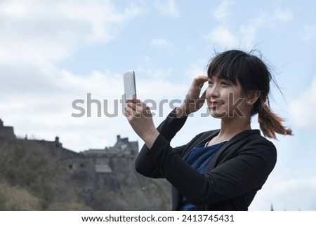Happy Chinese woman, taking self portrait with her phone Camera Outdoors.