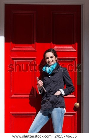 Portrait of a stylish caucasian woman standing by a red door. business or lifestyle image.