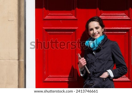 Portrait of a stylish caucasian woman standing by a red door. business or lifestyle image.