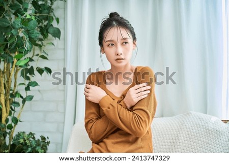 A young woman who is not feeling well wearing loungewear indoors Royalty-Free Stock Photo #2413747329