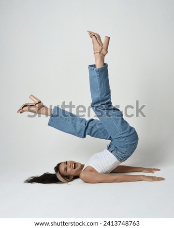Full length portrait of brunette female asian model wearing casual clothes, white singlet shirt, denim jean pants. Sitting pose, side down with legs in air.  high camera angle for perspective. Isolate