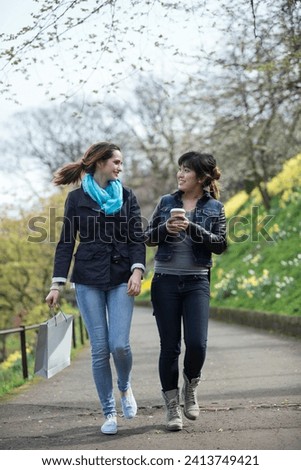 Two happy female friends out having fun together. Lifestyle image of Caucasian and Asian women. 