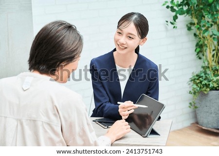 A woman in a suit explaining to a woman in plain clothes in the room Royalty-Free Stock Photo #2413751743