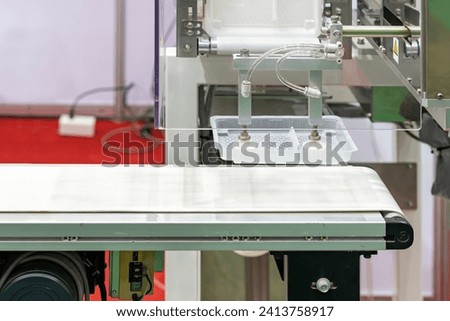 close up precision vacuum suction cup gripper with automatic limb during sucking pick – place plastic box on belt conveyor transport in manufacturing process Royalty-Free Stock Photo #2413758917