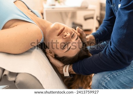 Osteopath performing a cervical adjustment on a relaxed female patient, enhancing neck mobility and relief. Royalty-Free Stock Photo #2413759927