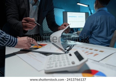Group of business people meeting, discussion, brainstorming, pointing at graphs and charts to analyze market data, calculating balance sheets, accounts, net profits to plan company sales strategies.