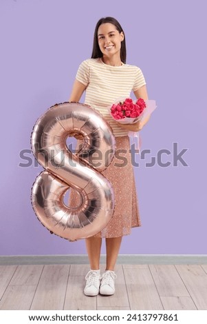 Young woman with tulips and balloon in shape of figure 8 near lilac wall. International Women's Day
